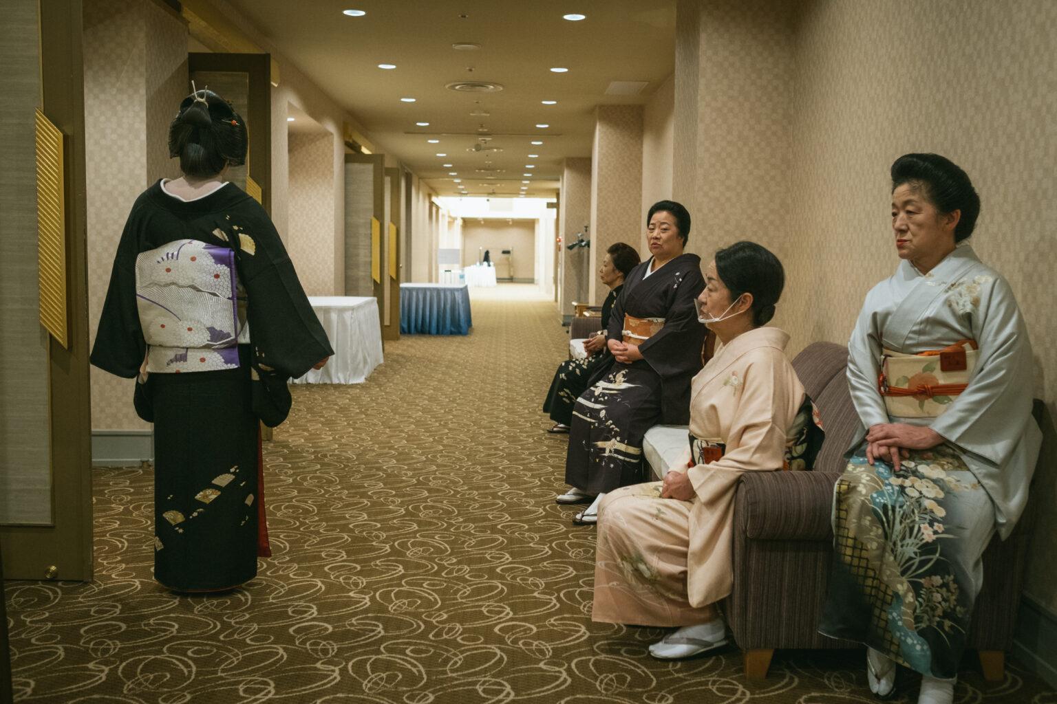 Geishas sitting on a sofa waiting.